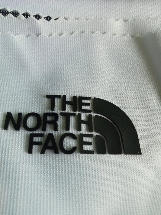 A factory worker ensuring a perfect heat press application of a custom TPU badge onto a black sports garment.
