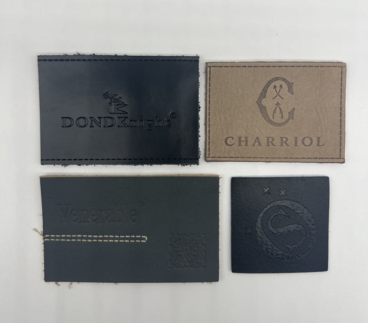 Close-up of a custom embossed brown genuine leather patch stitched onto the waistband of blue denim jeans