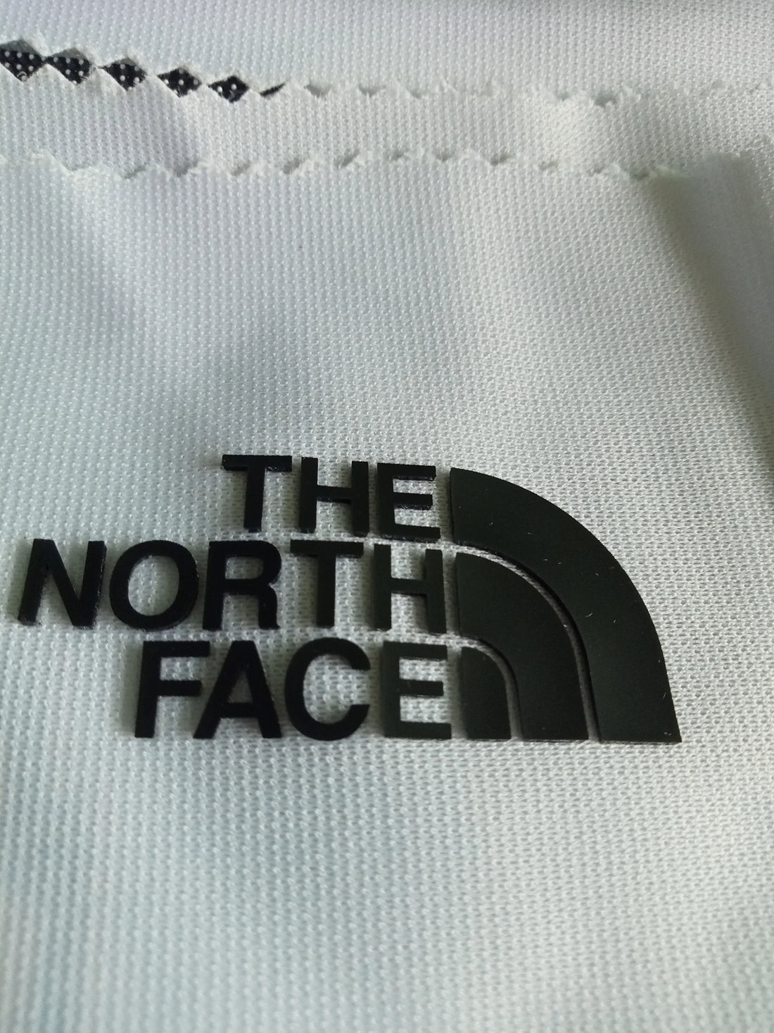 A factory worker ensuring a perfect heat press application of a custom TPU badge onto a black sports garment.